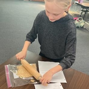 Participant crushing graham crackers in a bag using a rolling pin.