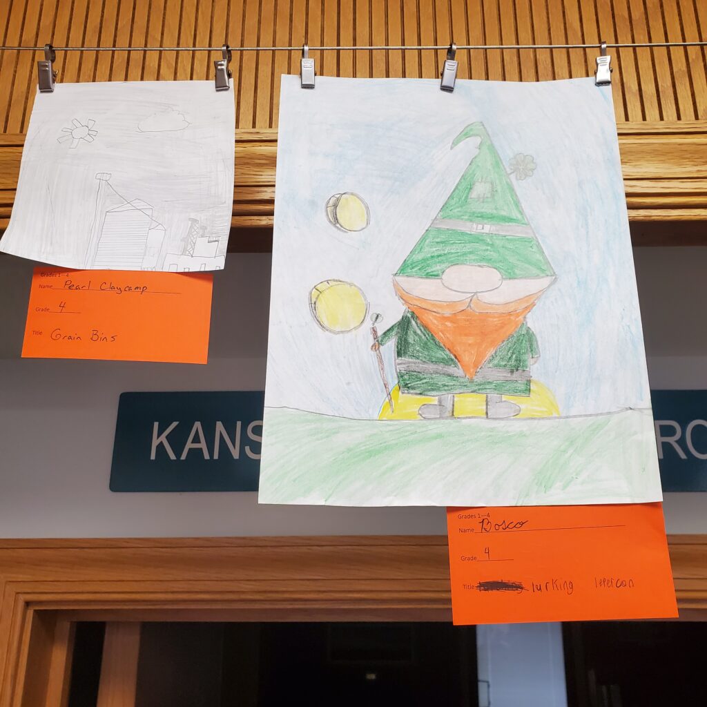 Left pencil sketch of a house and silo. Right a colored pencil sketch of a leprechaun and floating coins.