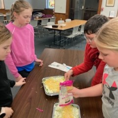 Participants add cheese layer to 7-layer salad.