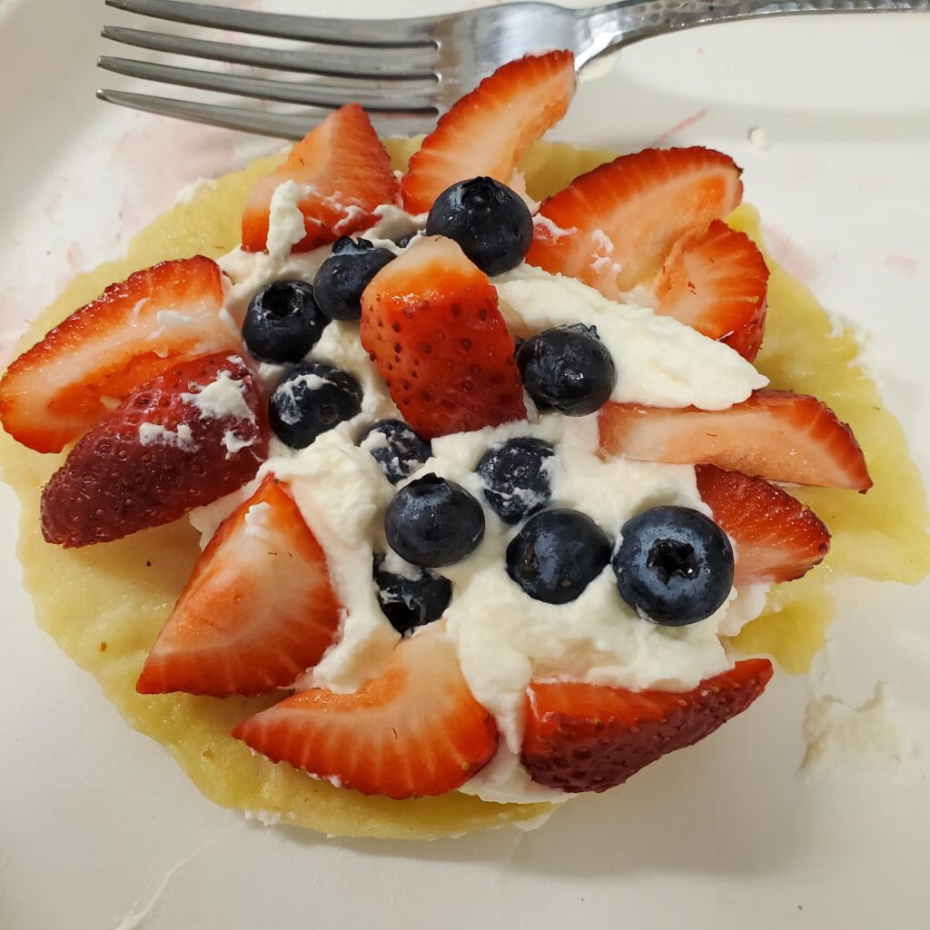 A fully loaded crepe with whipped creme, strawberry wedges, and blueberries.