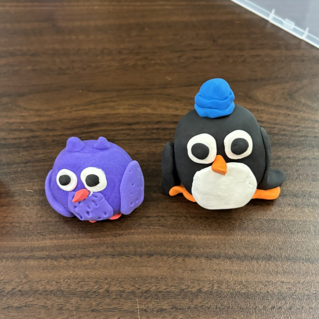 Owl and penguin wearing a blue beanie in clay.