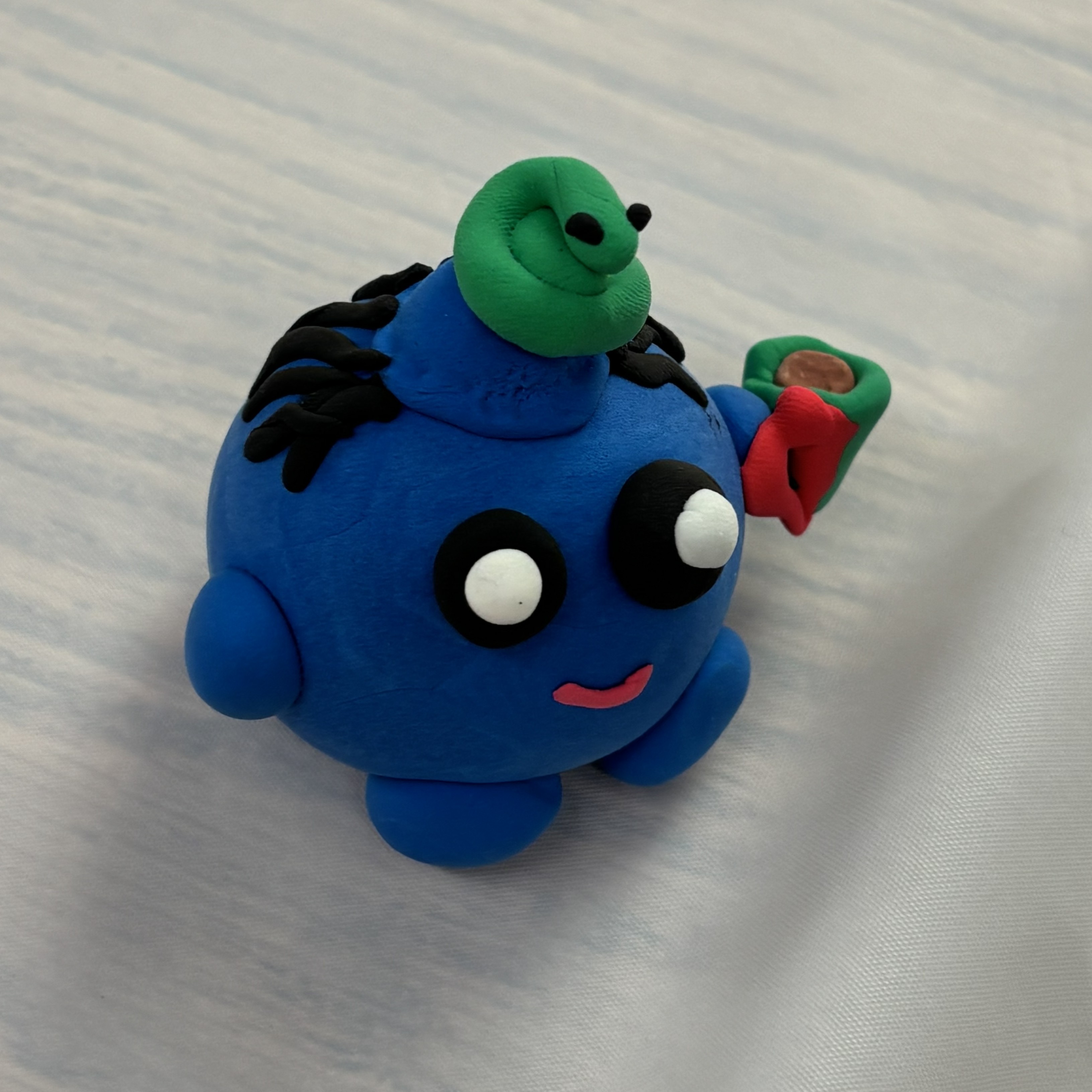 Blue cartoon figure with a snake on head in clay.