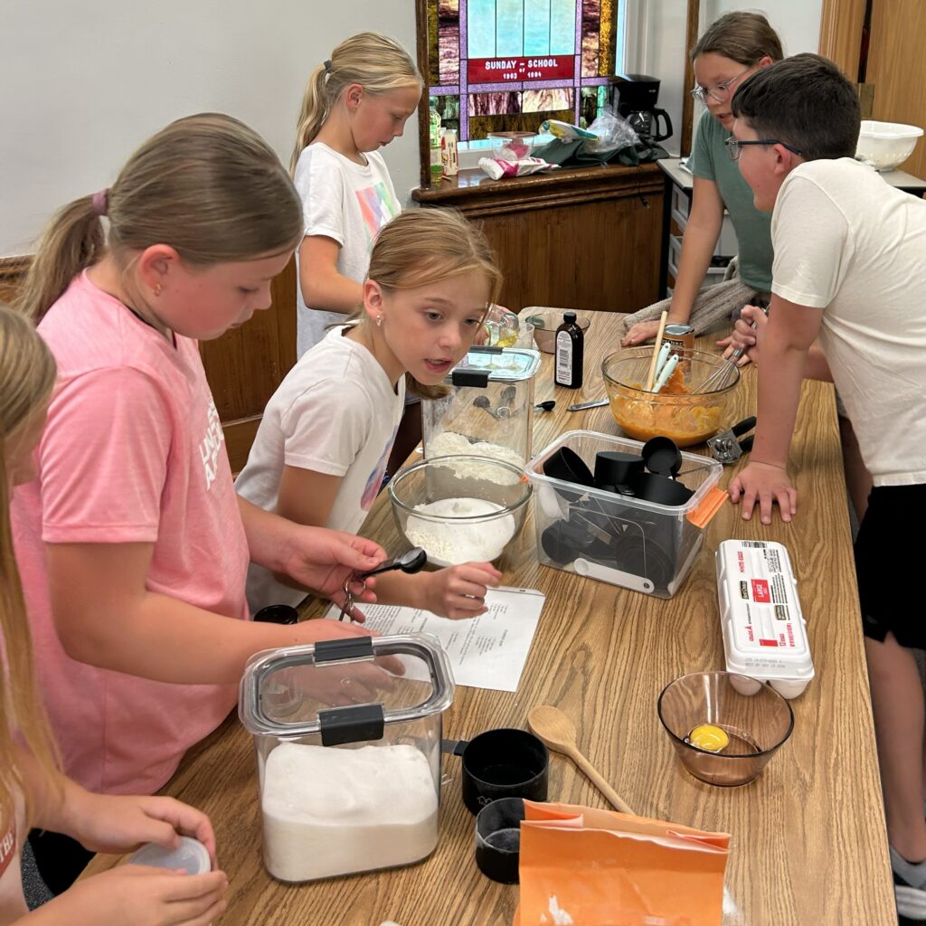 Kids reading recipes and mixing ingredients.